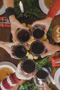 hands holding red wine in glasses clinking them together for a cheers.